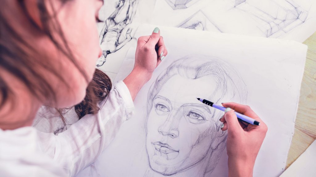 Conociendo mejor el trabajo de nuestros alumnos Alumna dibujando a lápiz el retrato de una mujer sobre una mesa