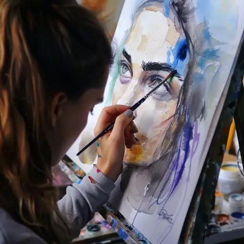 Cómo Dibujar y Pintar con Acuarelas: Guía Paso a Paso para Principiantes Artista pintando un retrato en acuarela sobre un papel colocado en un caballete