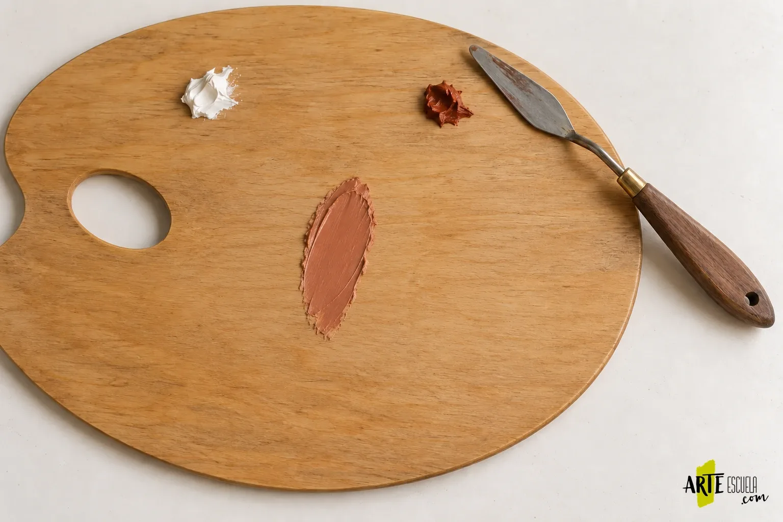 Paleta para óleo: cómo preparar la superficie y comparar tus mezclas sin perder pintura Pequeña prueba de mezcla terracota extendida sobre una paleta para óleo con espátula