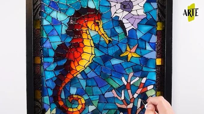 Taller de pintura sobre vidrio: copas y vidrieras Proceso de pintura de una vidriera con caballito de mar, fondo azul y formas delimitadas por contornos oscuros